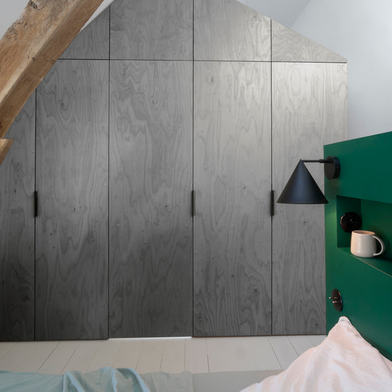 Ambiance chambre avec portes de placard décorées avec le Badigeon teinte Aluminium, murs blancs et tête de lit verte 