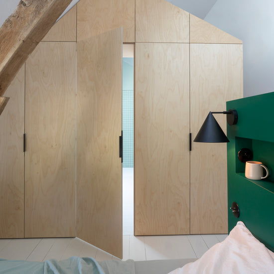 Ambiance chambre avec portes de placard décorées avec le Badigeon teinte Bois Brut, murs blancs et tête de lit verte 