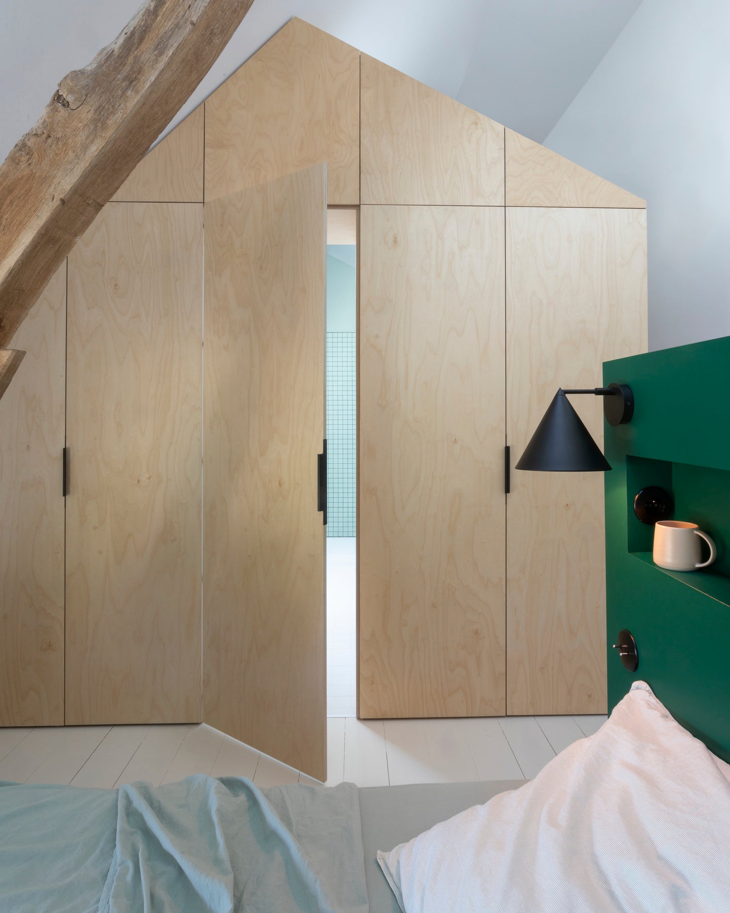 Ambiance chambre avec portes de placard décorées avec le Badigeon teinte Bois Brut, murs blancs et tête de lit verte 