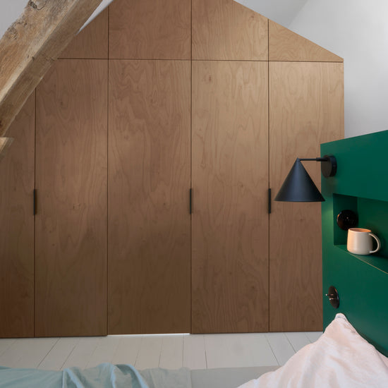 Ambiance chambre avec portes de placard décorées avec le Badigeon teinte Chêne Fumé, murs blancs et tête de lit verte 