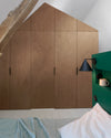 Ambiance chambre avec portes de placard décorées avec le Badigeon teinte Chêne Fumé, murs blancs et tête de lit verte 