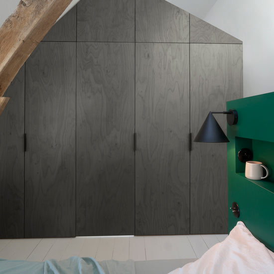 Ambiance chambre avec portes de placard décorées avec le Badigeon teinte Fonte Oxydée Libéron, murs blancs et tête de lit verte 
