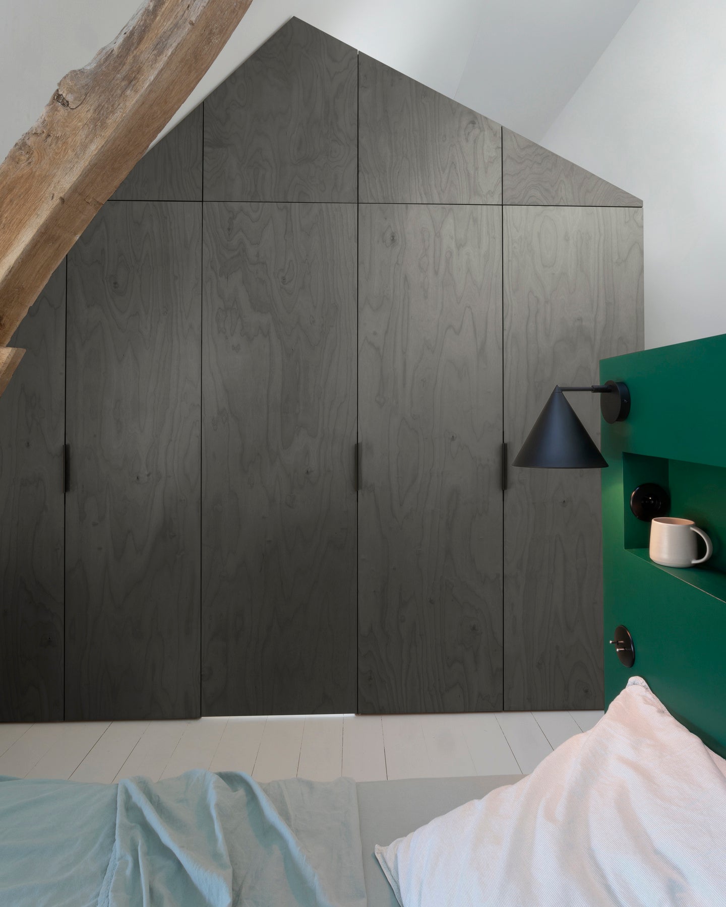 Ambiance chambre avec portes de placard décorées avec le Badigeon teinte Fonte Oxydée Libéron, murs blancs et tête de lit verte 