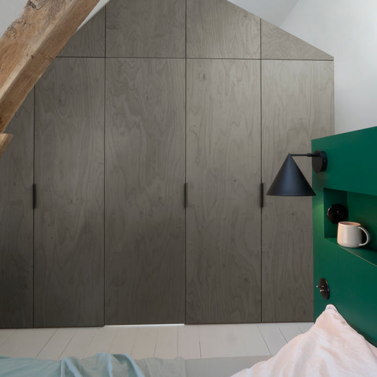 Ambiance chambre avec portes de placard décorées avec le Badigeon teinte Gris Fusain, murs blancs et tête de lit verte