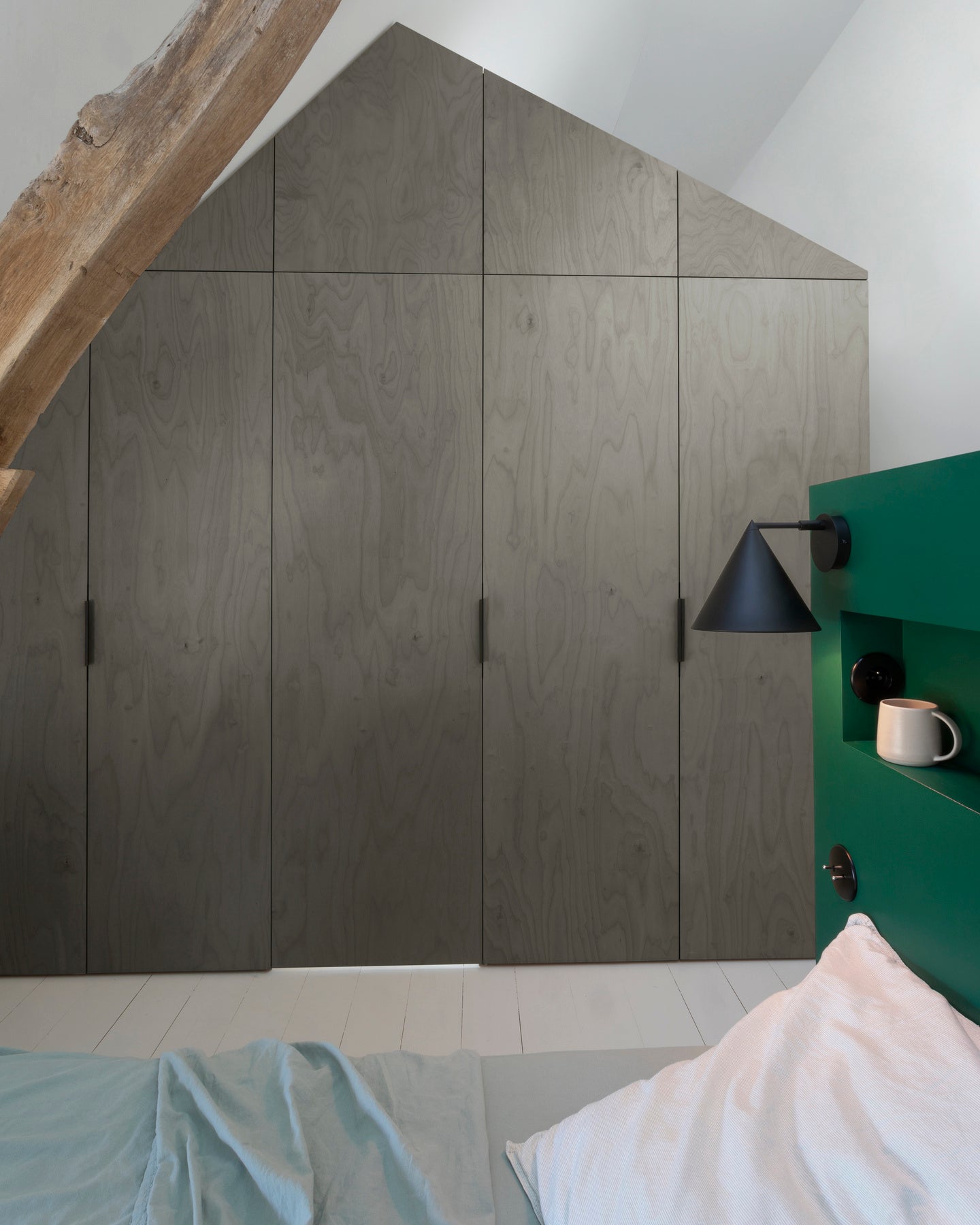 Ambiance chambre avec portes de placard décorées avec le Badigeon teinte Gris Fusain, murs blancs et tête de lit verte