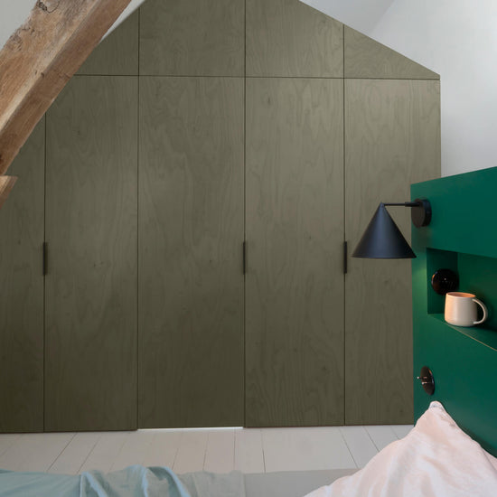 Ambiance chambre avec portes de placard décorées avec le Badigeon teinte Kaki Grisé, murs blancs et tête de lit verte