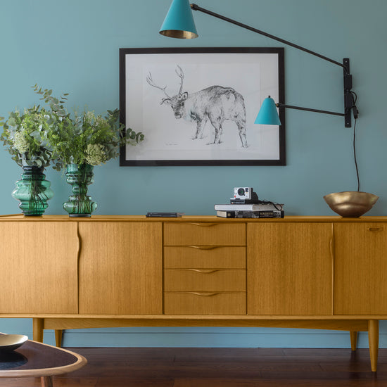 Buffet en bois ciré avec la Cire Black Bison Chêne Clair Libéron, dans un salon lumineux, avec vases verts, appliques bleues et déco vintage Libéron.