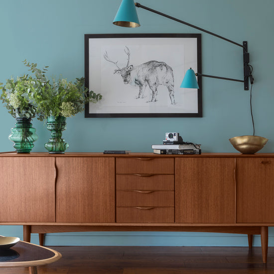 Buffet en bois ciré avec la Cire Black Bison Chêne Moyen Libéron, dans un salon lumineux, avec vases verts, appliques bleues et déco vintage Libéron.