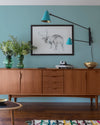Buffet en bois ciré avec la Cire Black Bison Chêne Moyen Libéron, dans un salon lumineux, avec vases verts, appliques bleues et déco vintage Libéron.