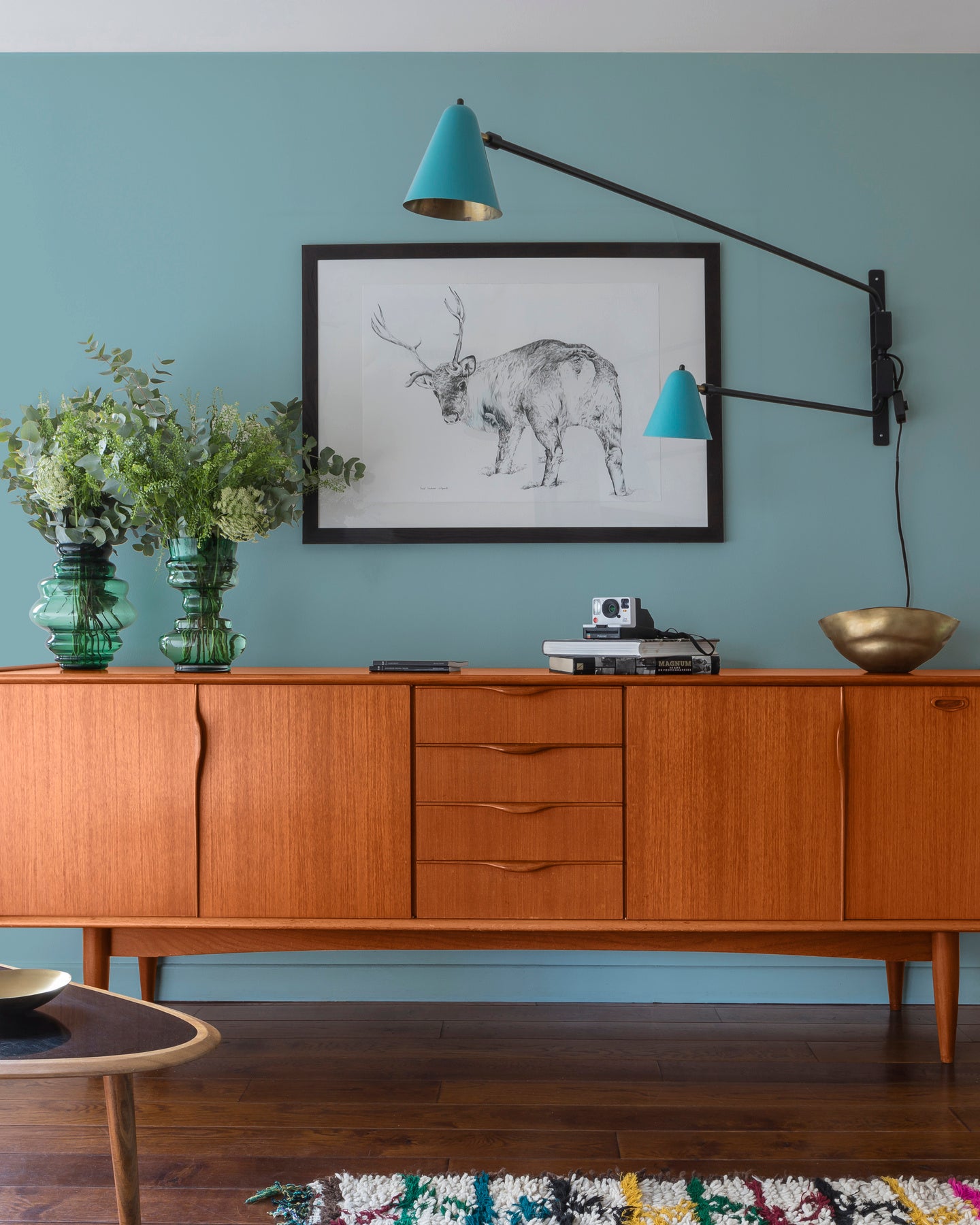 Buffet en bois ciré avec la Cire Black Bison Merisier Foncé Libéron, dans un salon lumineux, avec vases verts, appliques bleues et déco vintage Libéron.