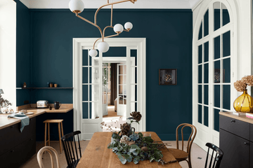 Cuisine lumineuse avec portes et fenêtres blanches, chaises et plan de travail en bois, table en bois avec bouquet de fleurs, et murs peints avec la peinture Libéron.