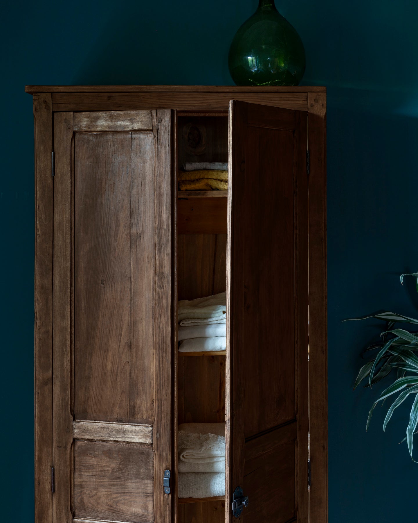 Armoire cirée avec La Crème de Cire teinte Chêne Cendré Libéron, murs bleu foncé, vase vert et plante