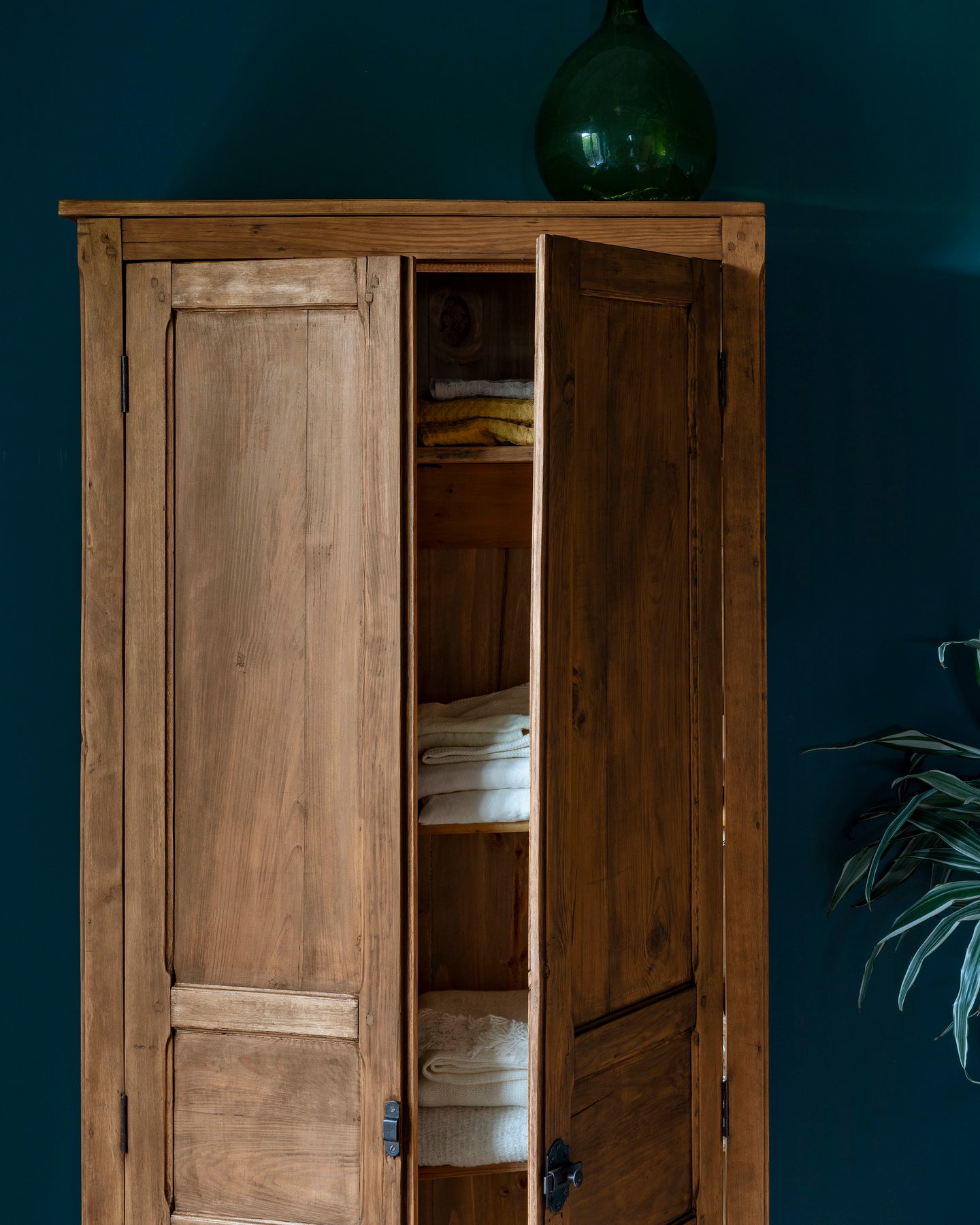 Armoire cirée avec La Crème de Cire teinte Chêne Doré Libéron, murs bleu foncé, vase vert et plante