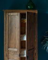 Armoire cirée avec La Crème de Cire teinte Noyer Fumé Libéron, murs bleu foncé, vase vert et plante