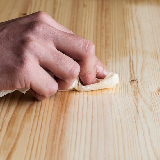 Main appliquant le Détachant Libéron  sur une surface en bois