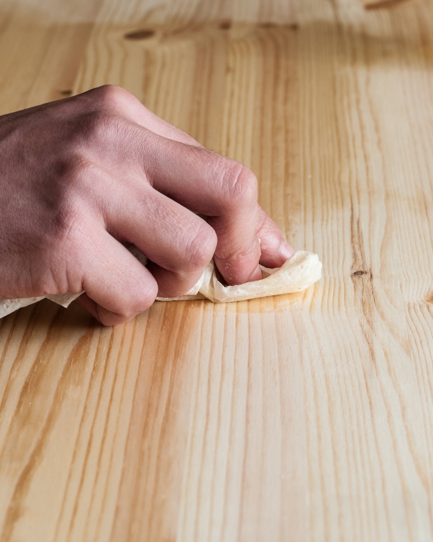 Main appliquant le Détachant Libéron  sur une surface en bois