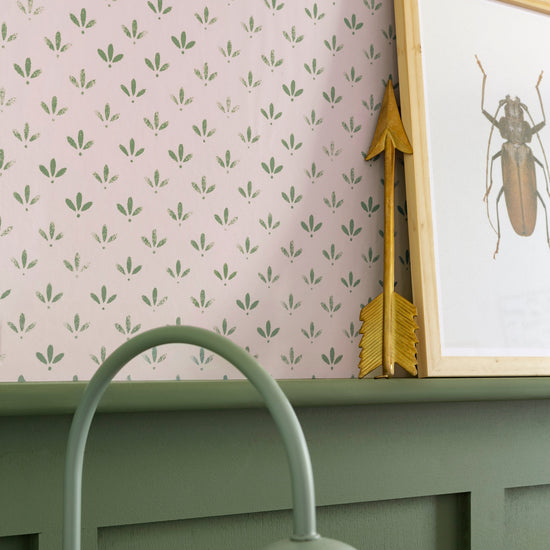 Détail de mur Florette Libéron, avec papier peint rose poudré à petit motif vert, soubassement vert sauge et cadre insecte.