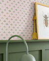 Détail de mur Florette Libéron, avec papier peint rose poudré à petit motif vert, soubassement vert sauge et cadre insecte.