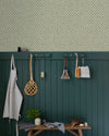 Entrée au mur Florette Libéron, avec papier peint crème à petit motif bleu, soubassement vert foncé, banc en bois et patères.