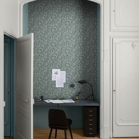 Coin bureau aux murs bleu grisé, Velours de Peinture Libéron Oeillet de reine, avec papier peint fleuri, chaise noire et porte blanche.