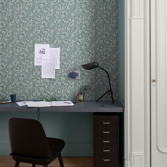 Bureau au mur floral vert d’eau et blanc, teinte Œillet Reine Libéron, avec chaise noire, lampe noire et soubassement bleu.