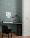 Bureau au mur floral vert d’eau et blanc, teinte Œillet Reine Libéron, avec chaise noire, lampe noire et soubassement bleu.