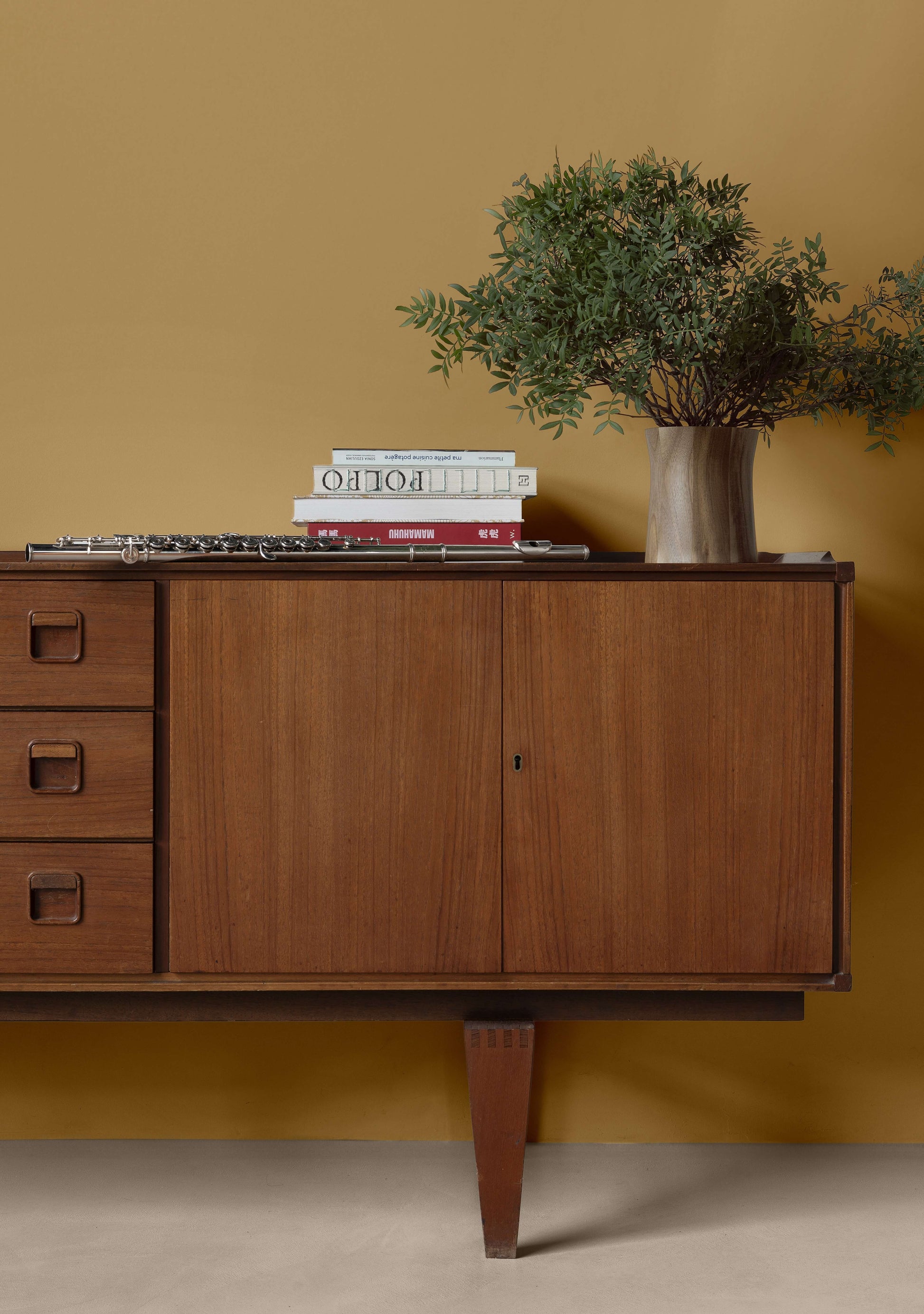 Salon aux murs jaunes et commode huilée avec l'Huile Soin Libéron, avec plantes vertes et livres