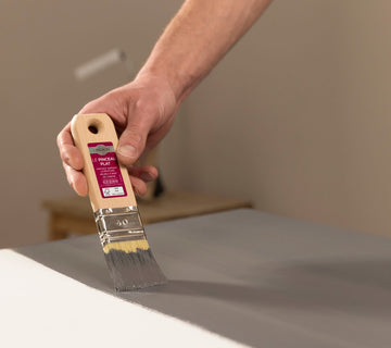 Application au pinceau d’une peinture effet béton gris Libéron sur un meuble blanc.