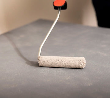 Application au rouleau d’une peinture effet béton gris Libéron sur un meuble, pour une finition minérale.