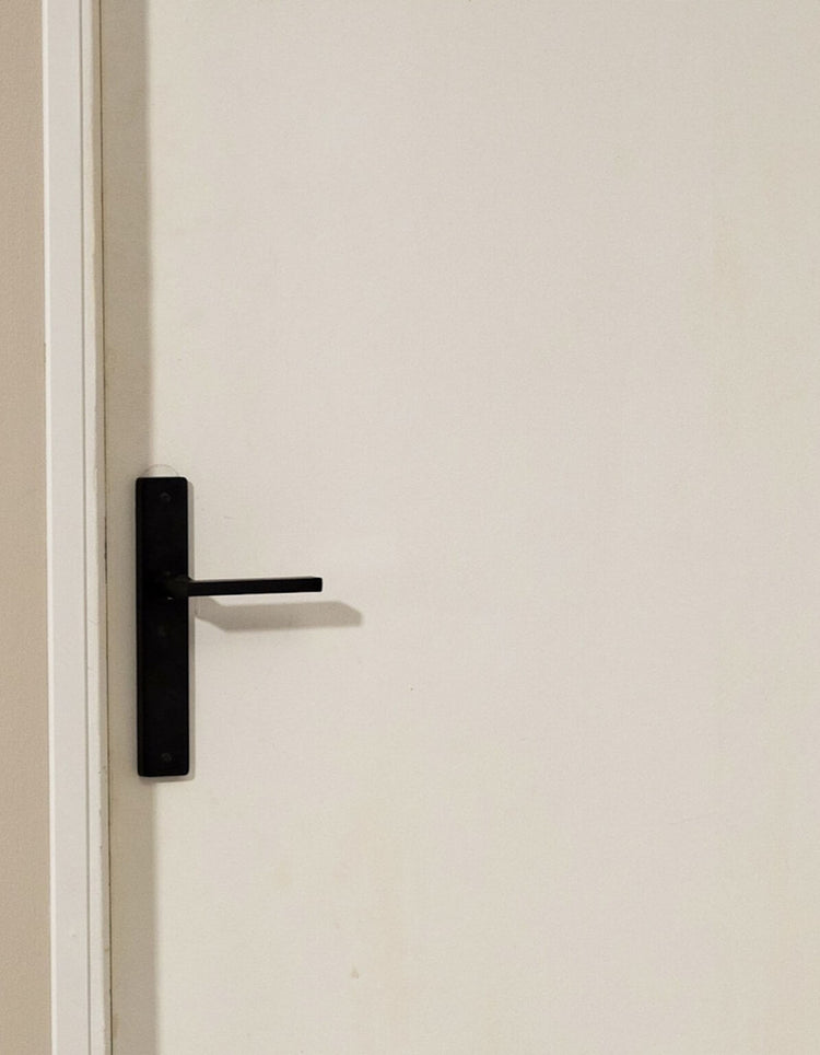 Porte blanche avant peinture effet bois Libéron, avec poignée noire et mur beige.