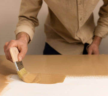 Application au pinceau d’une peinture effet bois Libéron sur une surface beige, avec veinage en cours.