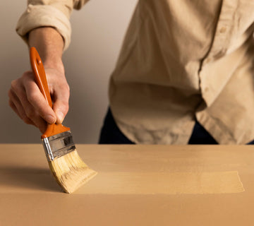 Application au pinceau d’une peinture effet bois Libéron sur une surface beige en cours de rénovation.