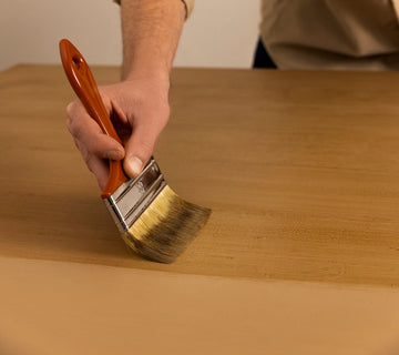 Application au pinceau d’une peinture effet bois Libéron sur une surface beige, avec veinage en cours de création.