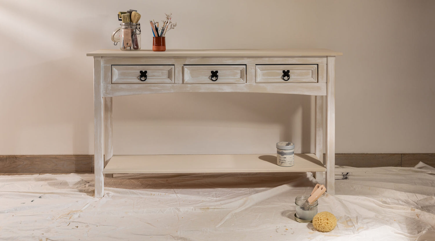 Console effet chaulé Libéron avec tiroirs patinés, pinceaux et pot Meuble signé dans une ambiance atelier.