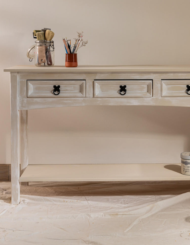 Console effet chaulé Libéron avec tiroirs patinés, boutons noirs et accessoires de peinture.