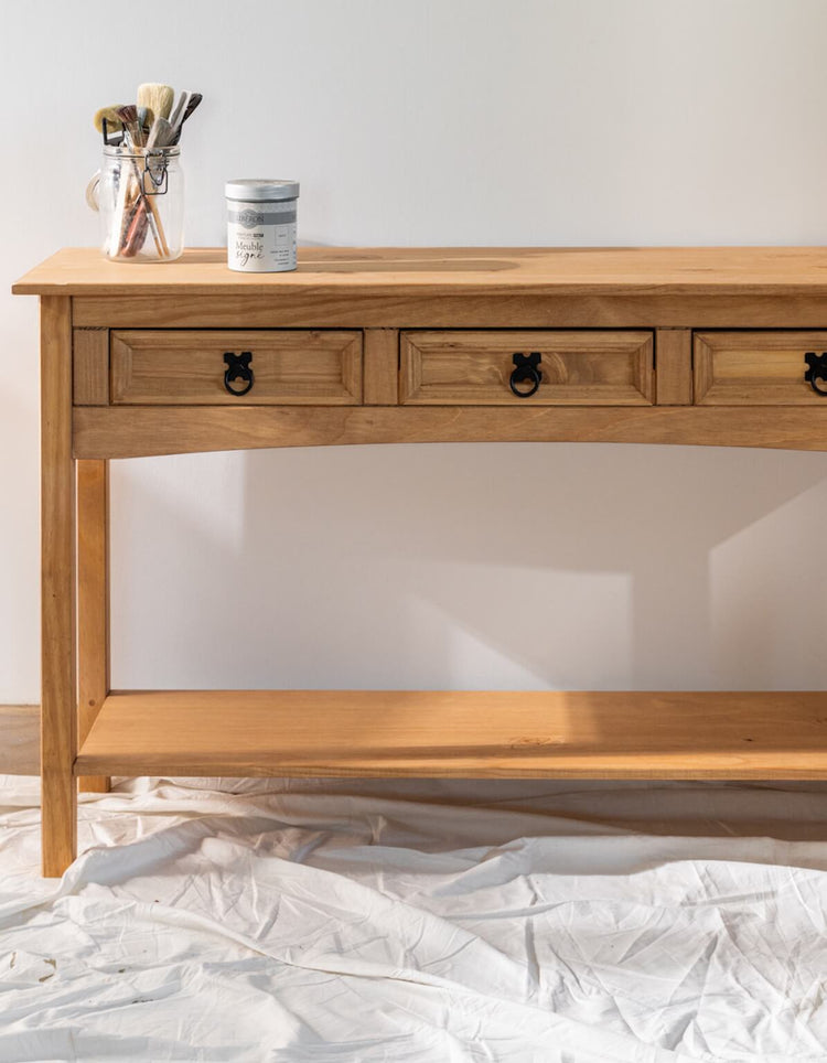 Console en bois brut avant effet chaulé Libéron, avec pot Meuble signé et pinceaux dans une ambiance atelier.