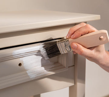 Application au pinceau d’un effet chaulé blanc Libéron sur un tiroir de console beige.