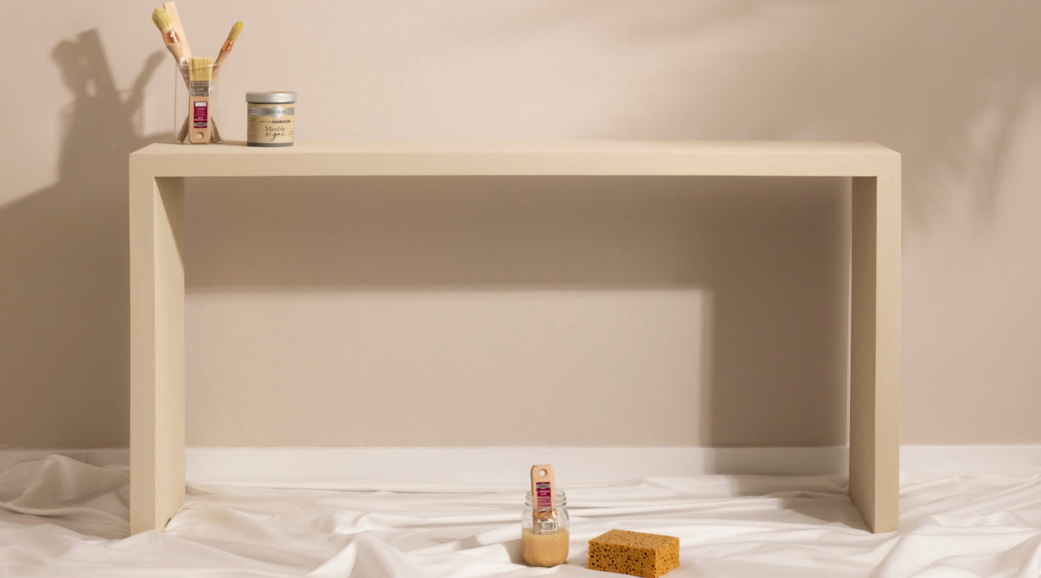 Console effet minéral beige Libéron, avec pinceaux, pot Meuble signé, éponge et toile de protection.