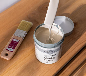 Pot de peinture mat Libéron Meuble signé en cours de mélange, avec pinceau sur meuble en bois.
