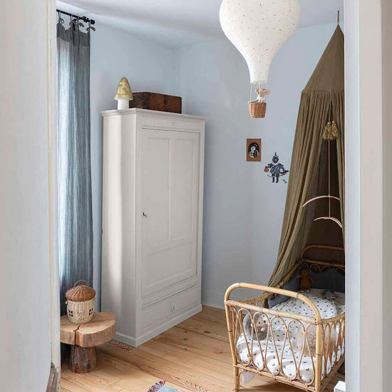 Ambiance d'une chambre d'enfant aux murs bleu, avec armoire blanche, peinture Meuble Signé Mat à base de Caséine teinte Crème Libéron