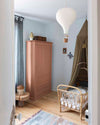 Ambiance d'une chambre d'enfant aux murs bleu, avec armoire rose, peinture Meuble Signé Mat à base de Caséine teinte Ocre Rose Libéron