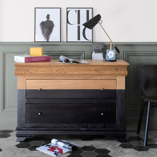 Commode en bois et noir brillant Libéron dans une ambiance bureau, avec mur vert grisé, lampe et affiches.