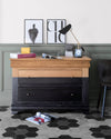Commode en bois et noir brillant Libéron dans une ambiance bureau, avec mur vert grisé, lampe et affiches.