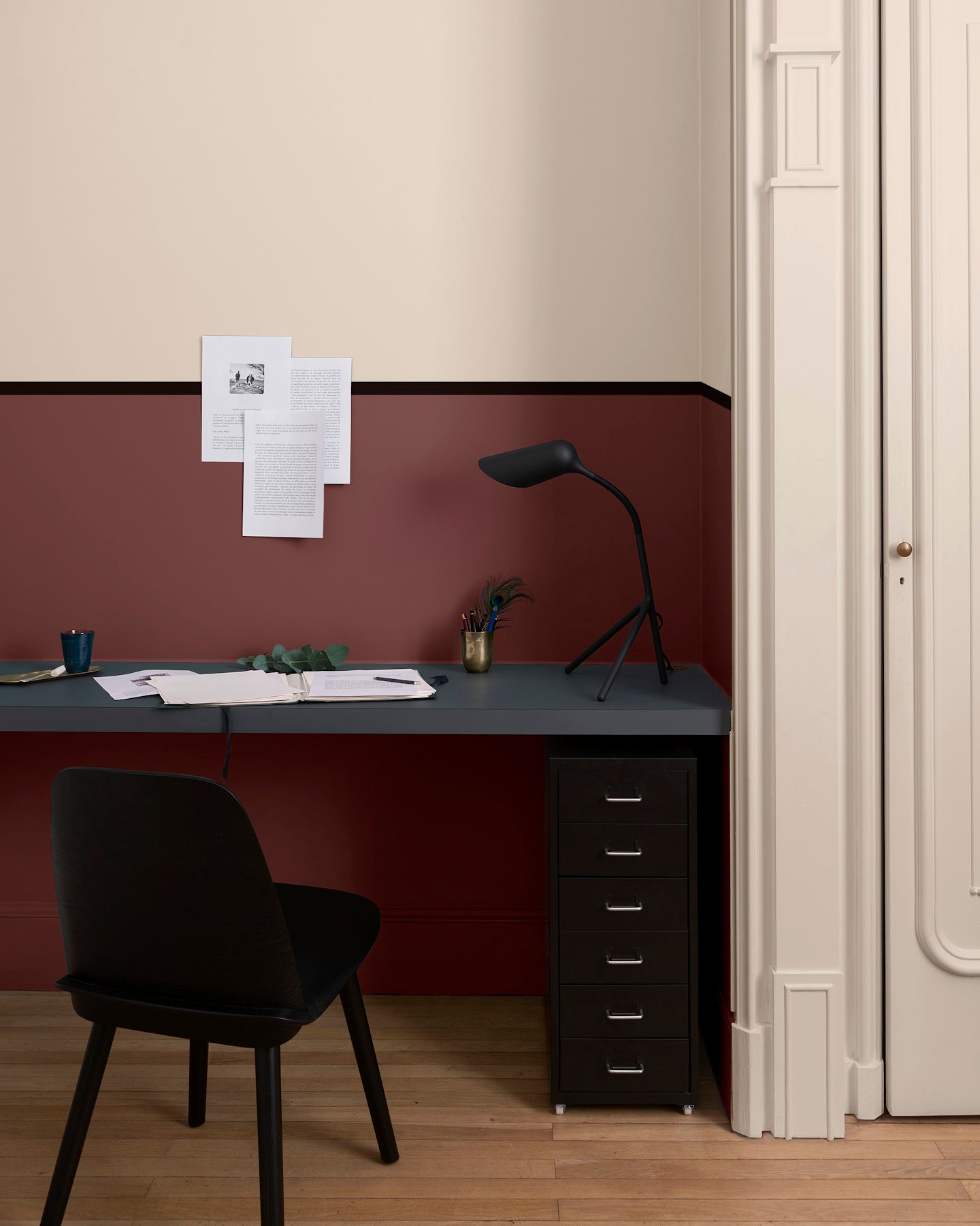 Coin bureau aux murs ambre blanc et bordeaux tomette Libéron, avec plateau noir, chaise noire et parquet.