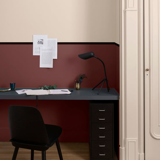 Coin bureau aux murs ambre blanc et bordeaux tomette Libéron, avec plateau noir, chaise noire et parquet.