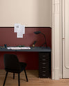 Coin bureau aux murs ambre blanc et bordeaux tomette Libéron, avec plateau noir, chaise noire et parquet.