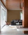Salon aux murs blanc mousseline et brun arabique Libéron, avec plafond bois, canapé sombre et fauteuil cuir.