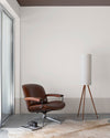 Salon épuré aux murs blanc mousseline et soubassement grège tapissier Libéron, avec fauteuil cuir et lampe sur pied.