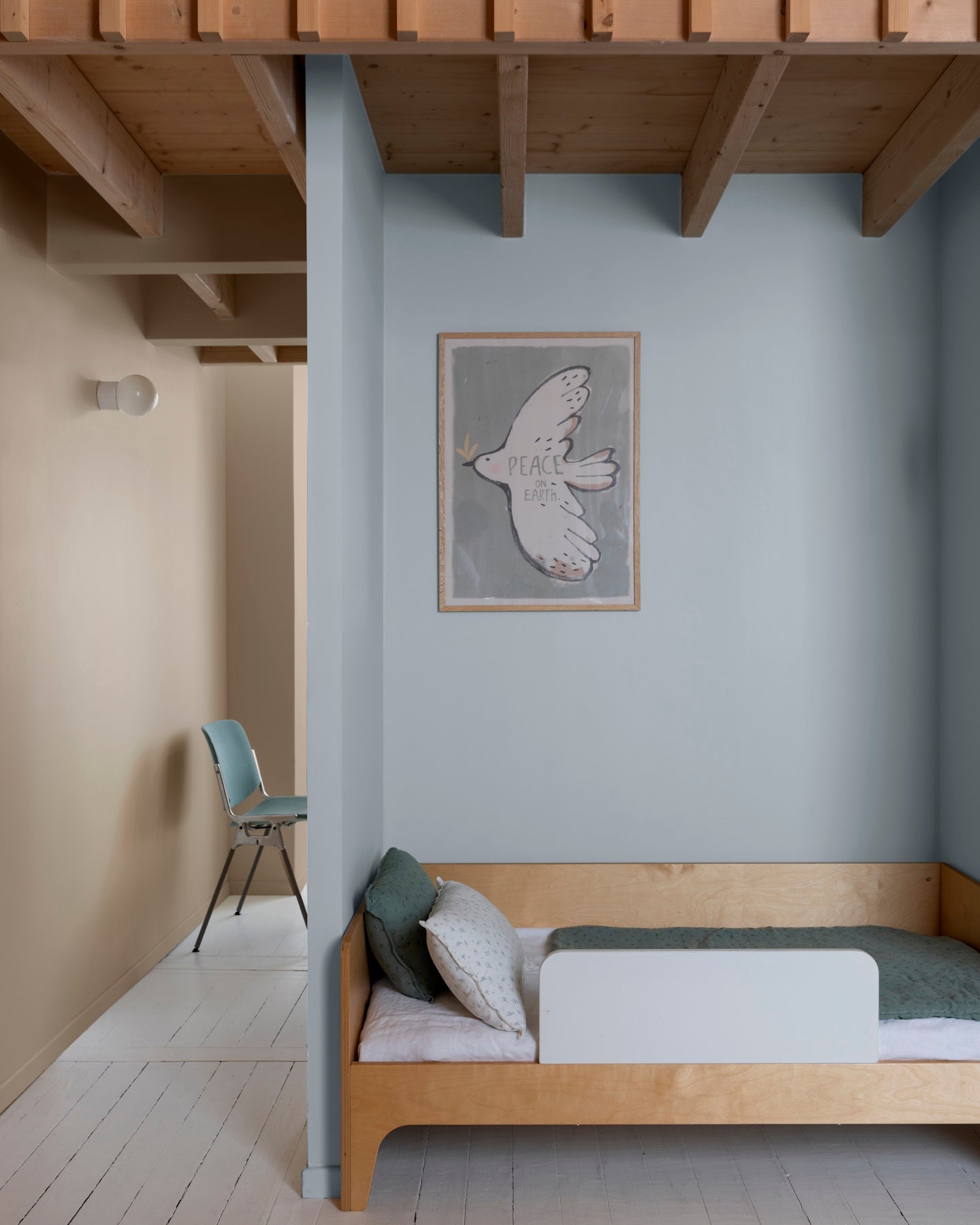 Chambre aux murs 163 Faubourg bleu couture et beige bottier Libéron, avec lit en bois, poutres apparentes et chaise bleue.