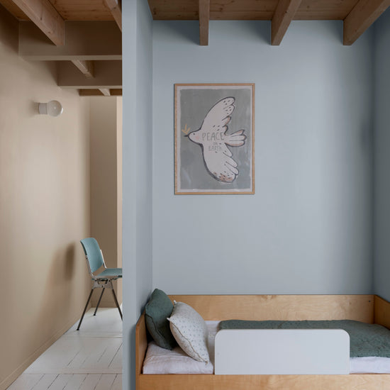 Chambre d’enfant aux murs bleu couture et beige bottier Libéron, avec lit en bois clair et plafond à poutres.